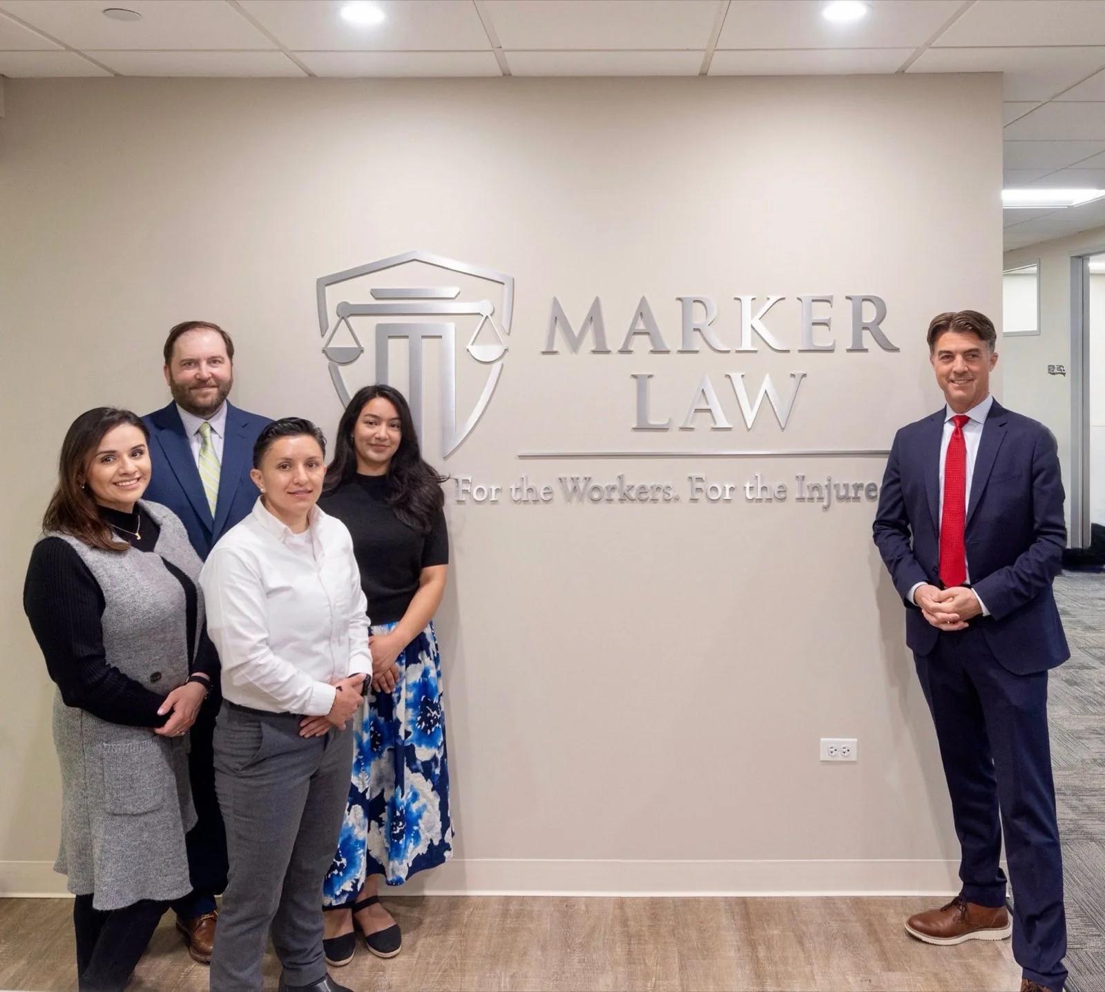 The Marker Law team standing together in front of the firm's lobby sign at the Naperville office