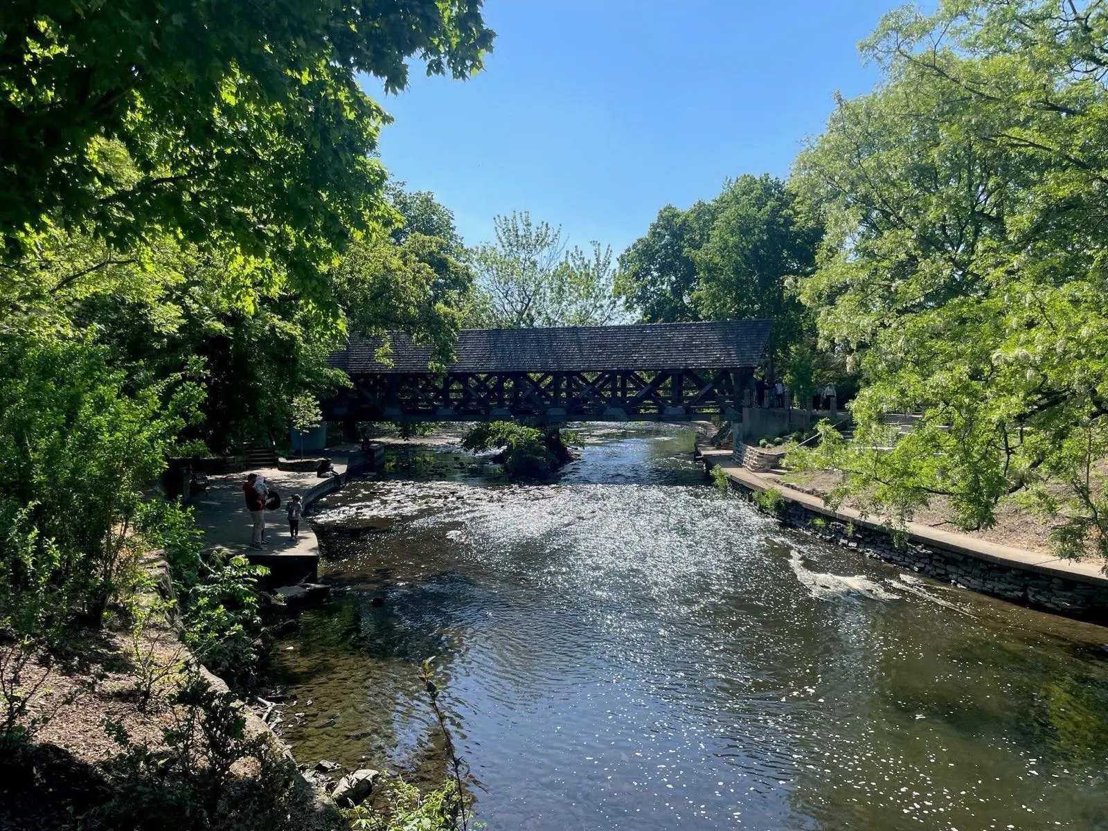 The covered bridge and river along the Naperville Riverwalk on a clear summer day