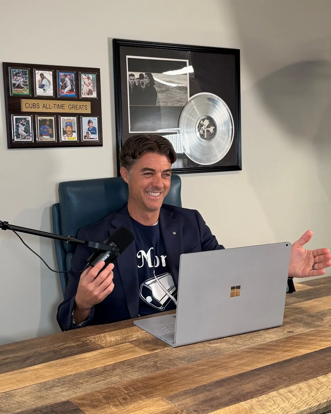 Jason A. Marker at the microphone recording The Briefcase and the Beat, with his Cubs All-Time Greats plaque and a framed platinum record on the wall behind him