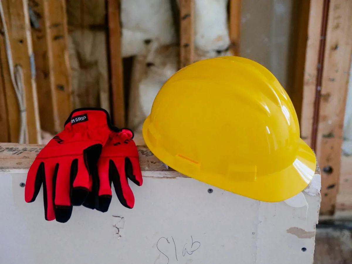 Yellow hard hat and work gloves resting on a board at a job site
